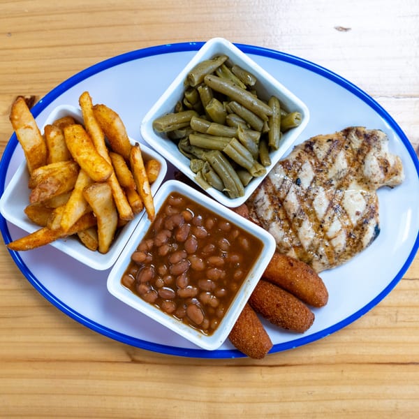 Grilled chicken, french fries, green beans, baked beans, and hushpuppies on a white and blue plate.