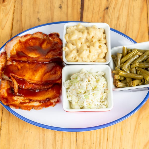 BBQ ham with macaroni and cheese, coleslaw, and green beans on a white plate.