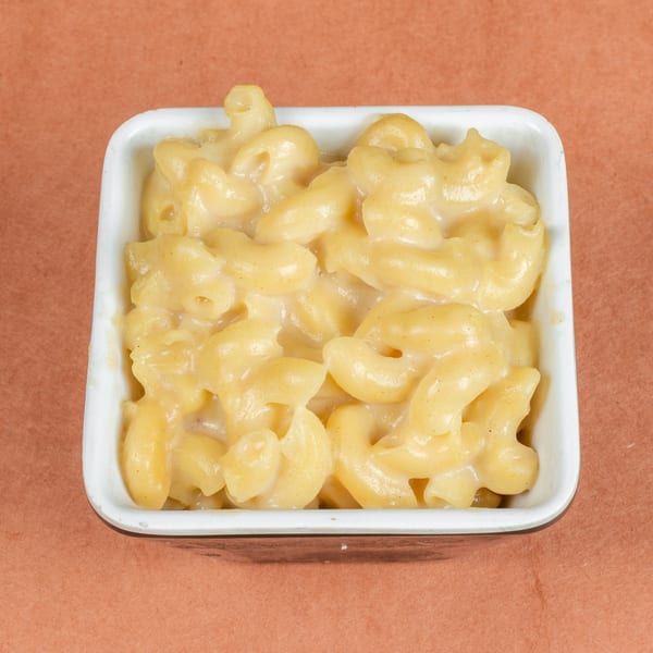 Creamy macaroni and cheese in a white rectangular dish on a brown surface.
