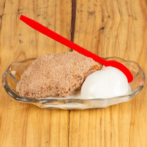 Cinnamon-sugar dessert with a scoop of vanilla ice cream and a red spoon in a glass dish.