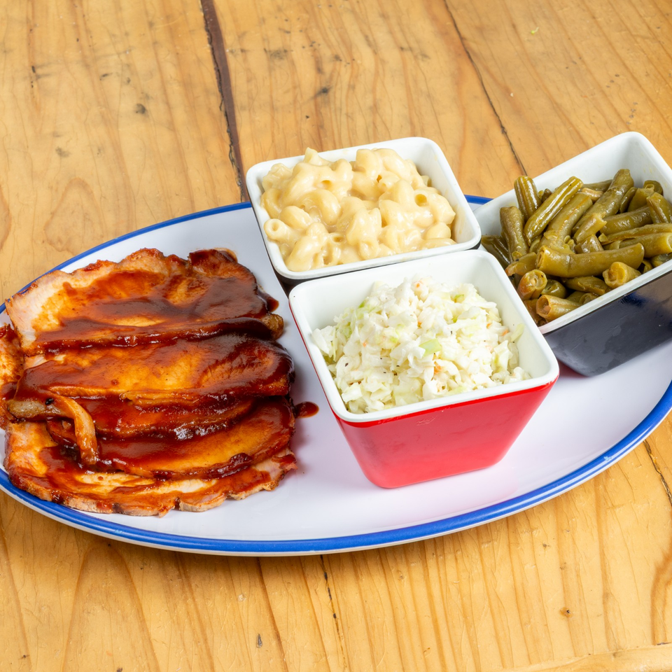 BBQ pork with mac and cheese, coleslaw, and green beans on a white plate.